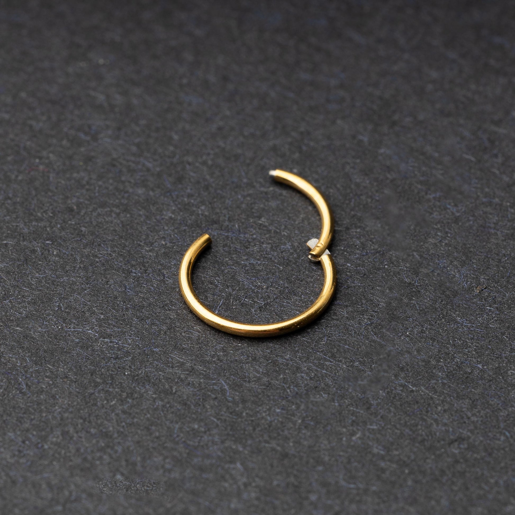 Gold seamless ring with a minimalist design, displayed on a dark background.