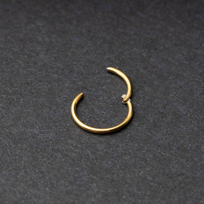 Gold seamless ring with a minimalist design, displayed on a dark background.