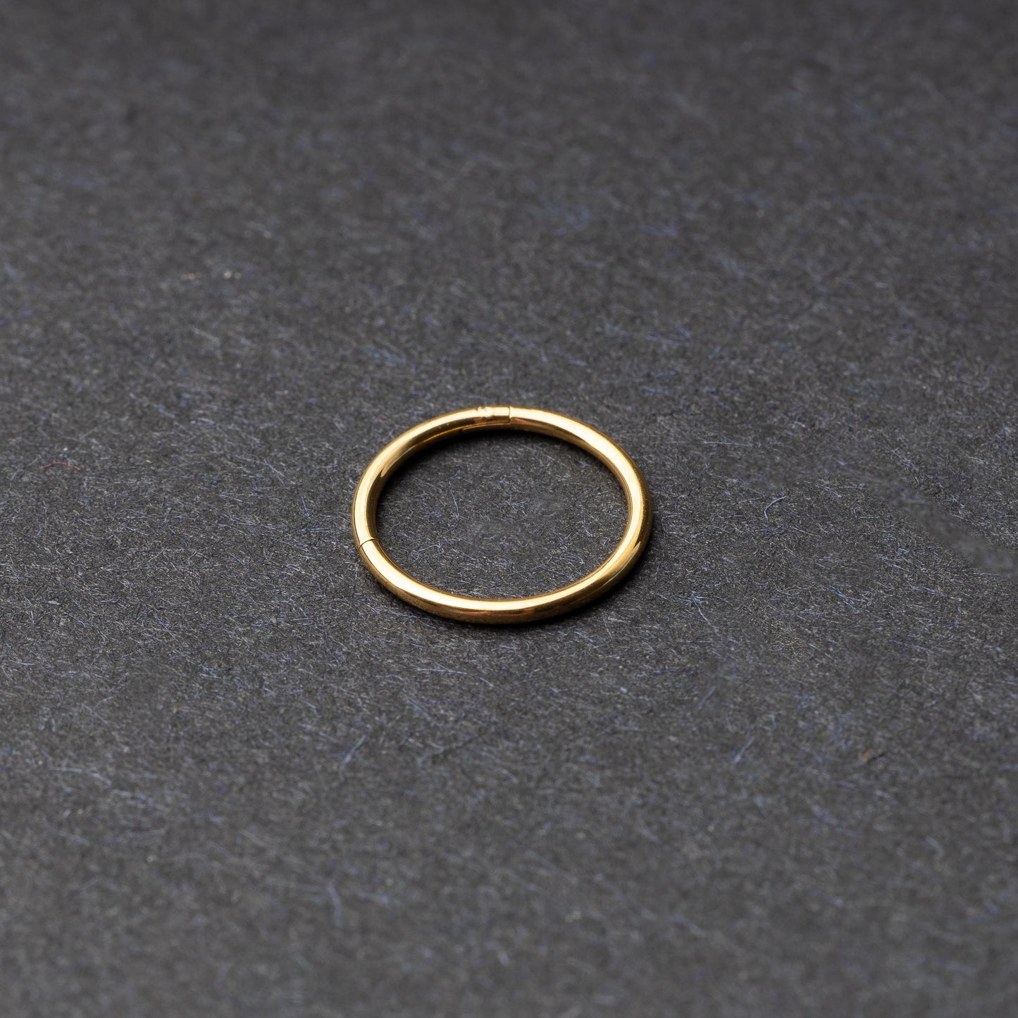 Gold seamless ring with a minimalist design, displayed on a dark background.