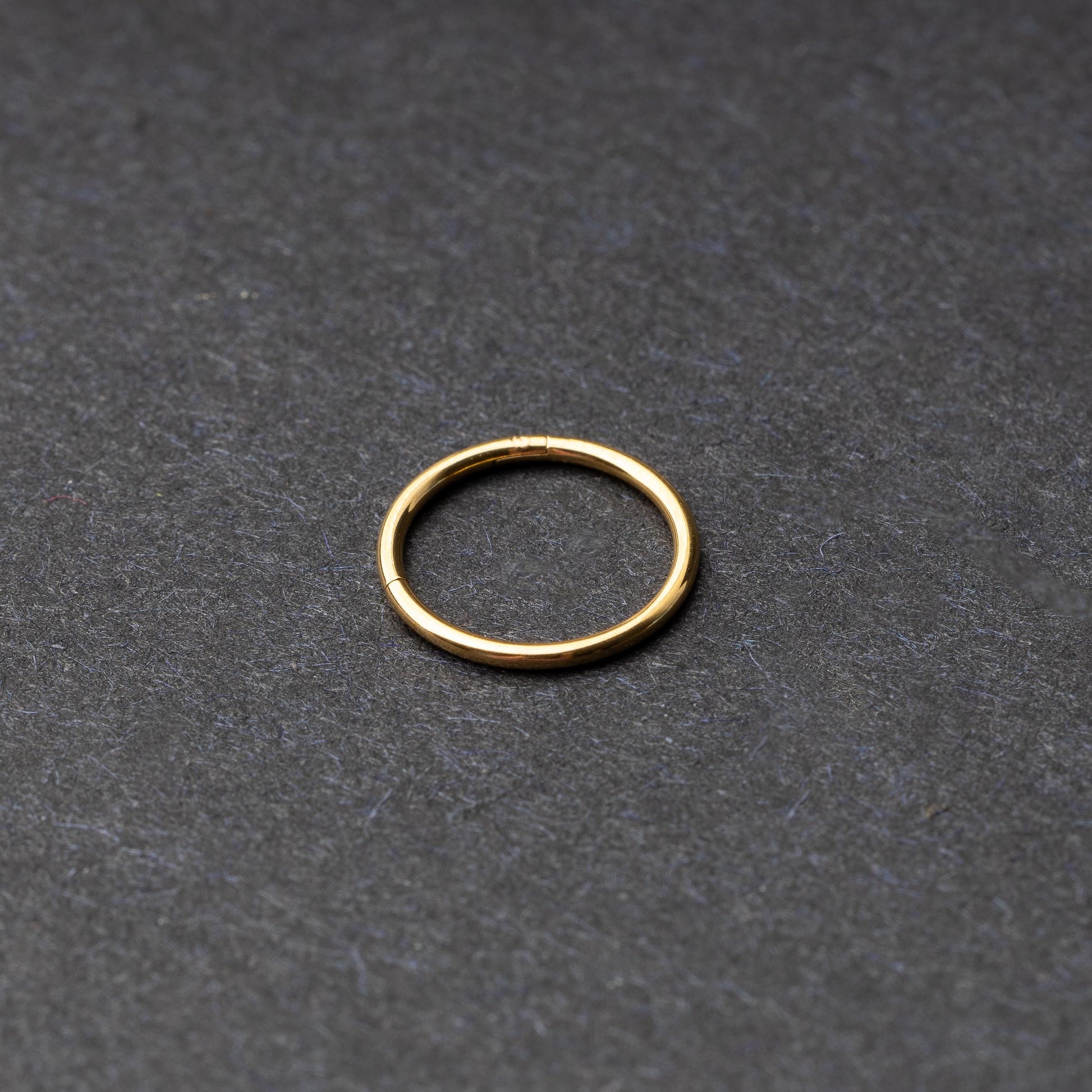 Gold seamless ring with a minimalist design, displayed on a dark background.