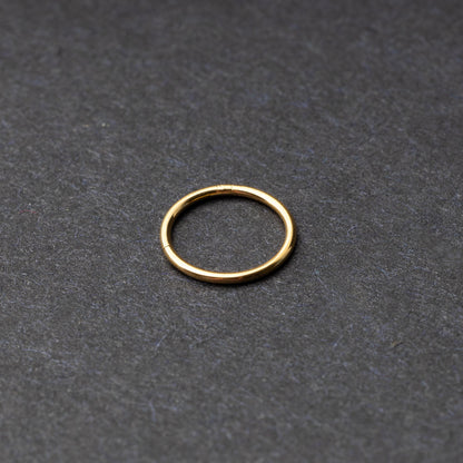 Gold seamless ring with a minimalist design, displayed on a dark background.