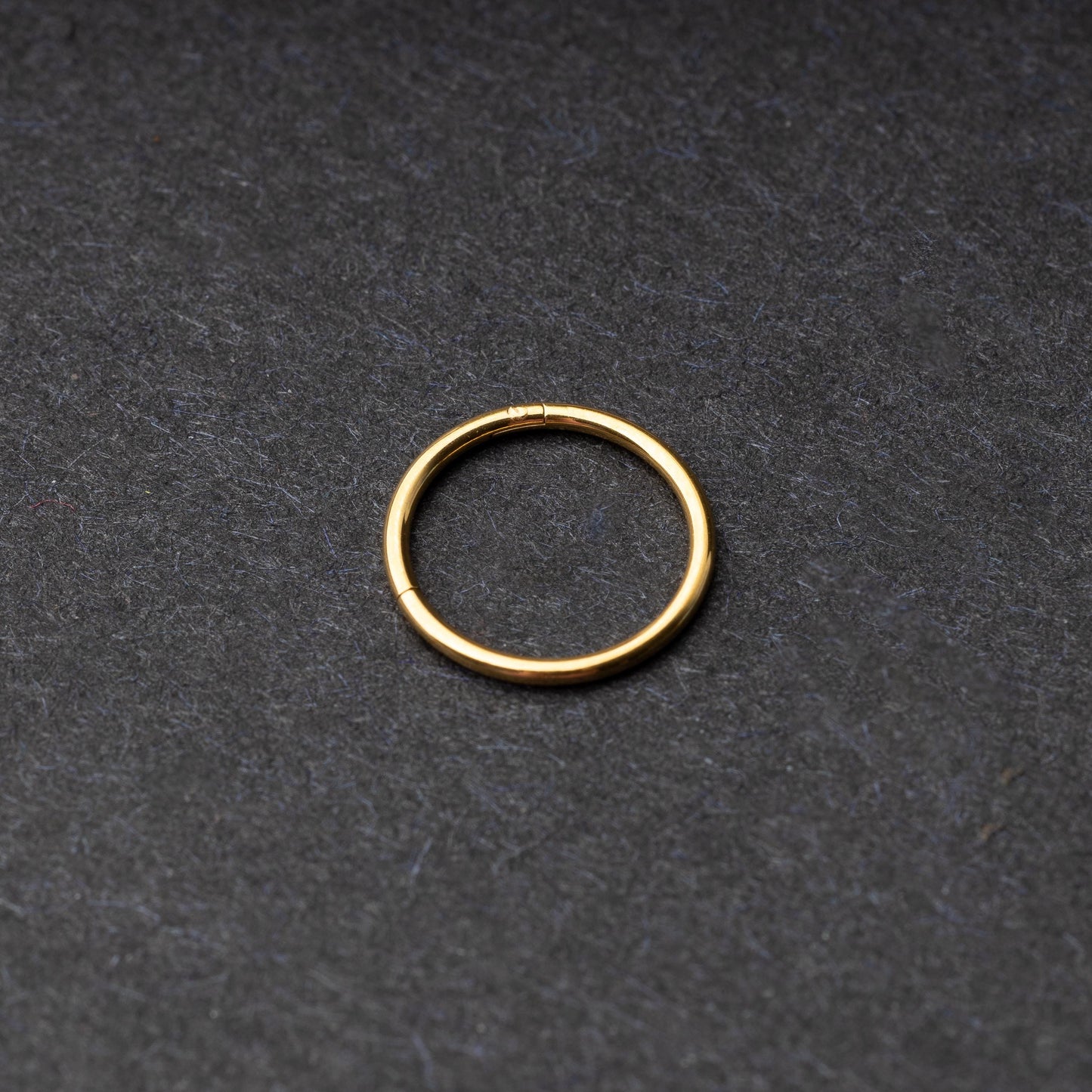 Gold seamless ring with a minimalist design, displayed on a dark background.