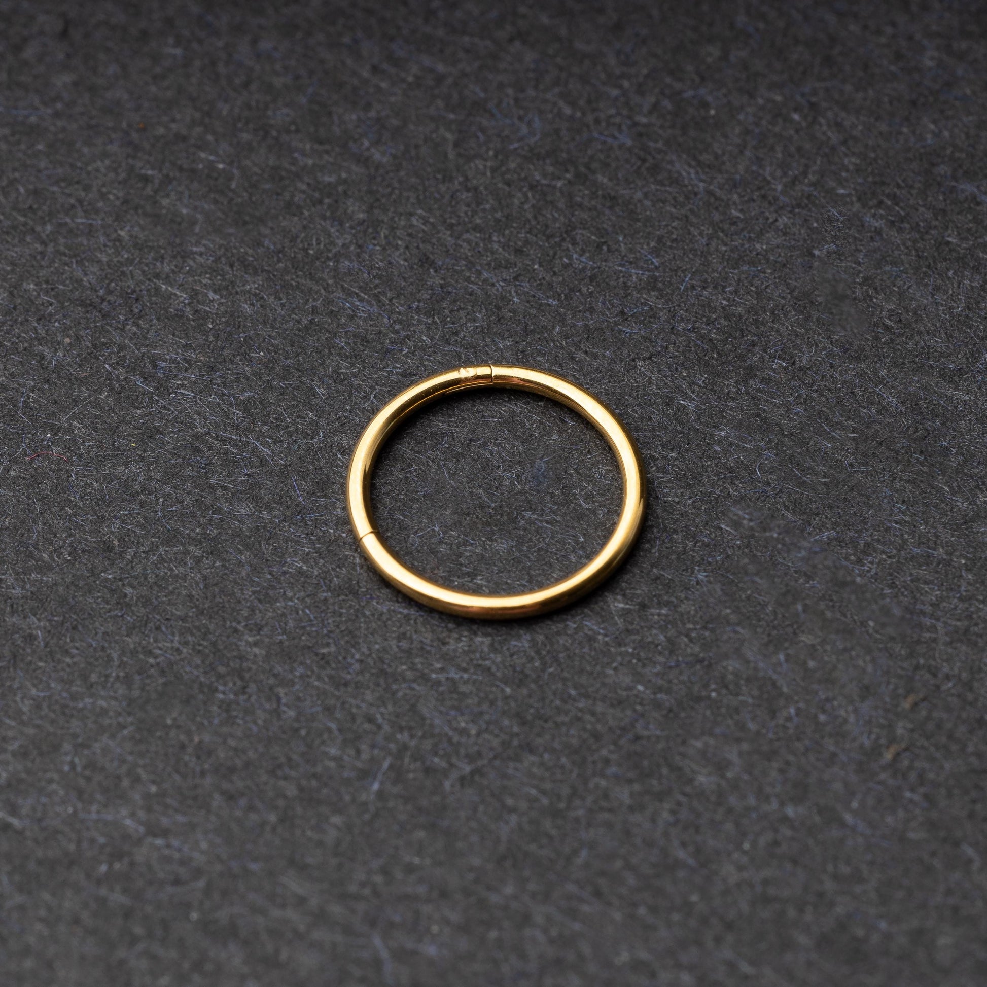 Gold seamless ring with a minimalist design, displayed on a dark background.