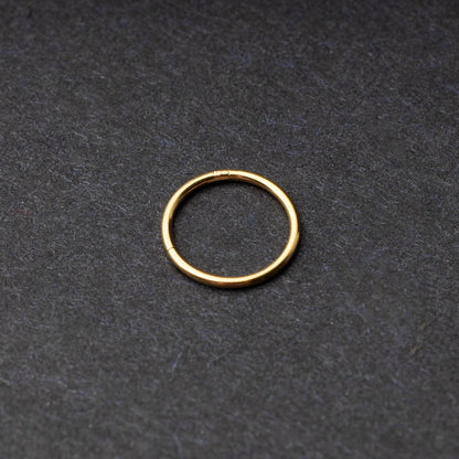Gold seamless ring with a minimalist design, displayed on a dark background.