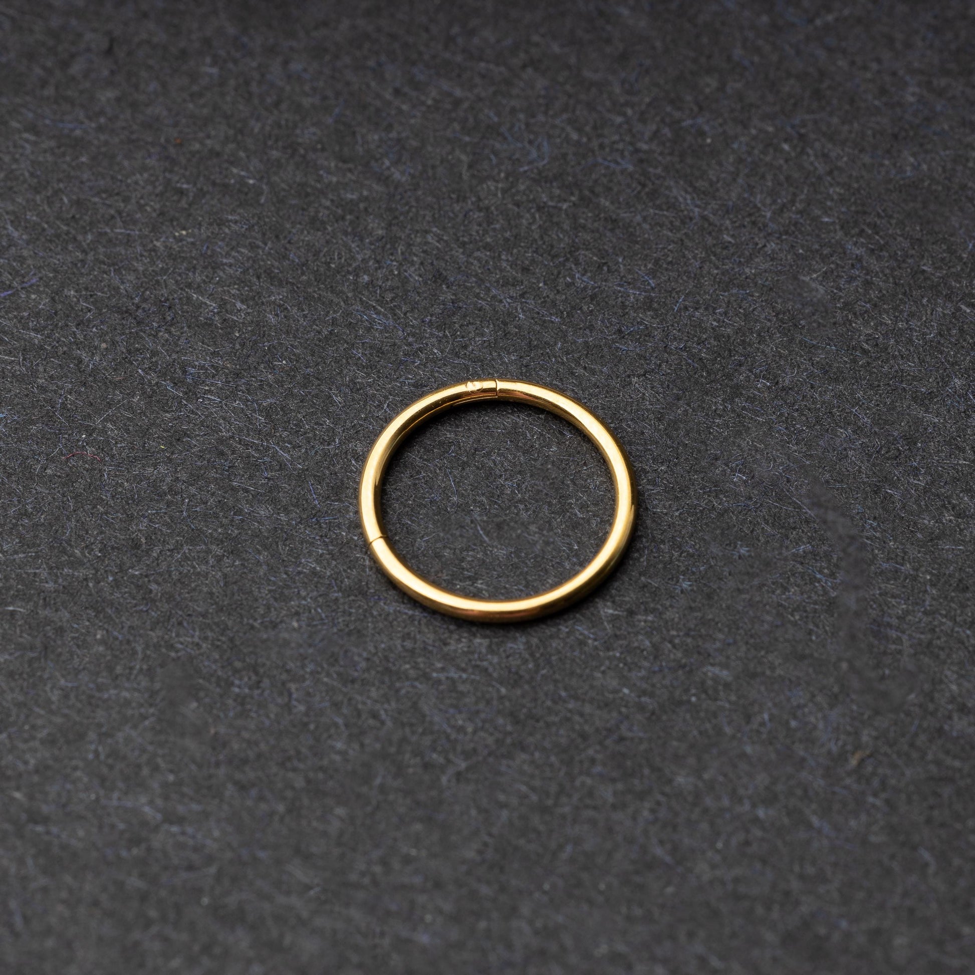 Gold seamless ring with a minimalist design, displayed on a dark background.