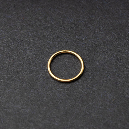 Gold seamless ring with a minimalist design, displayed on a dark background.