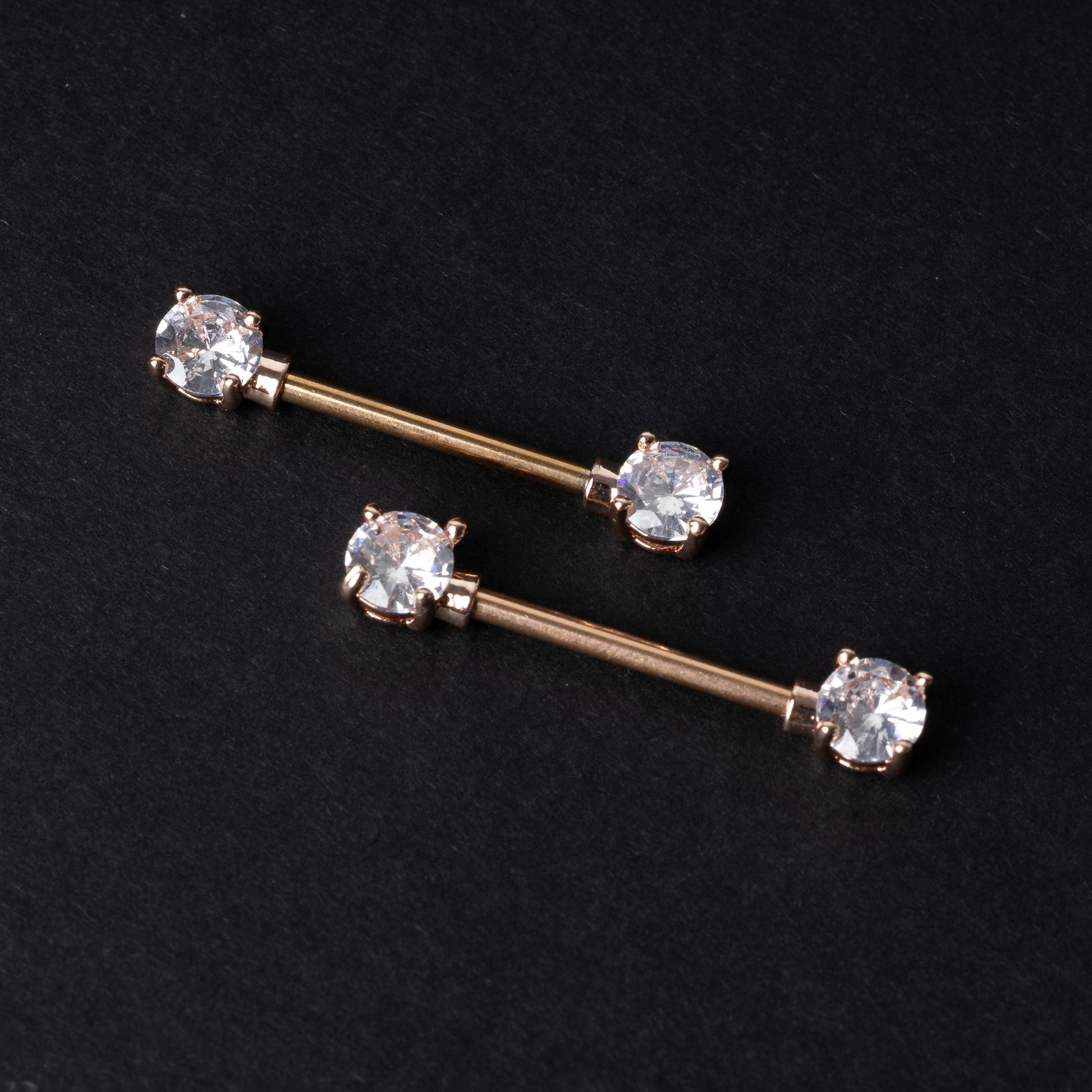 Crystal-studded barbells in gold displayed on a dark background.