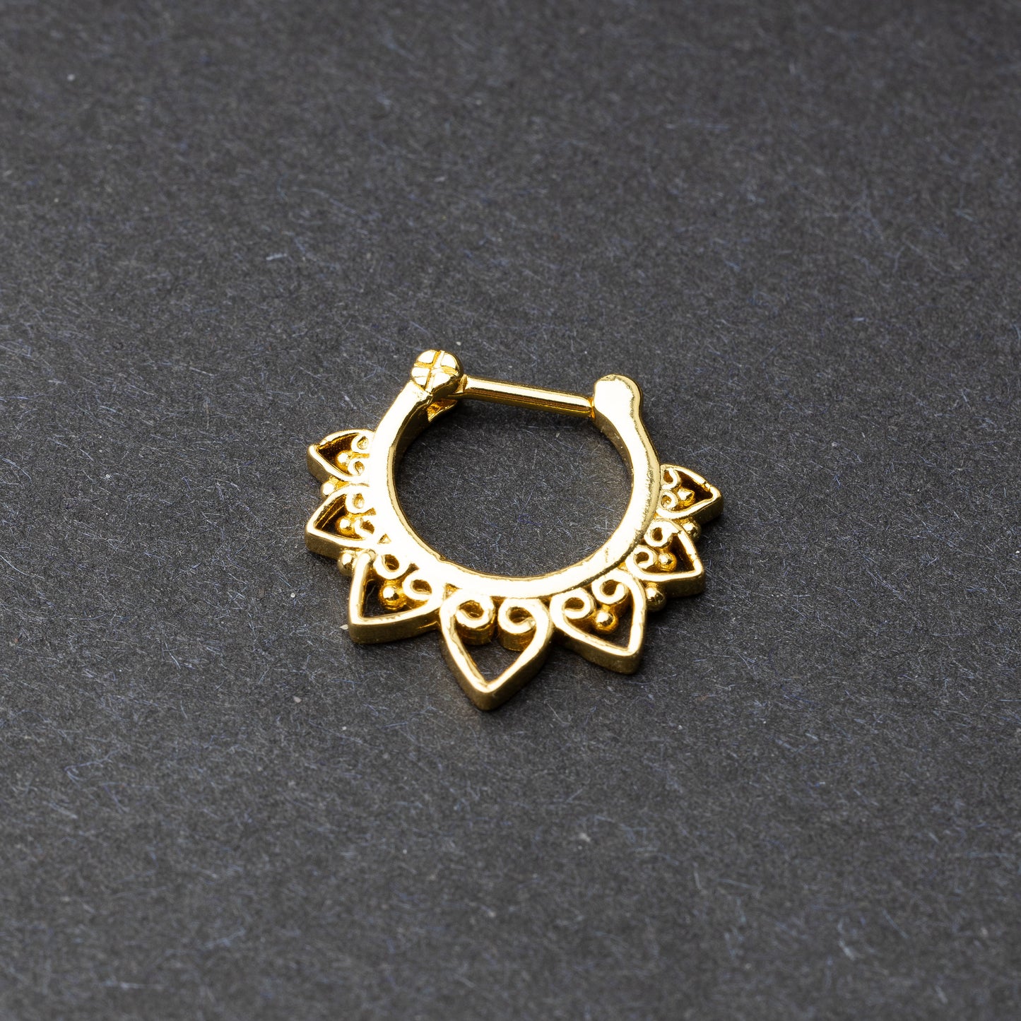 Gold septum clickers with intricate geometric and swirl detailing.