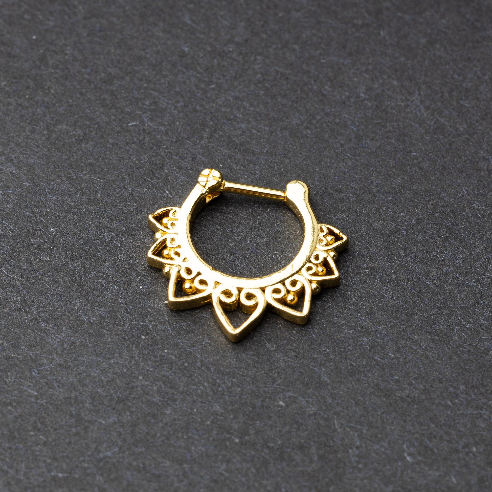 Gold septum clickers with intricate geometric and swirl detailing.