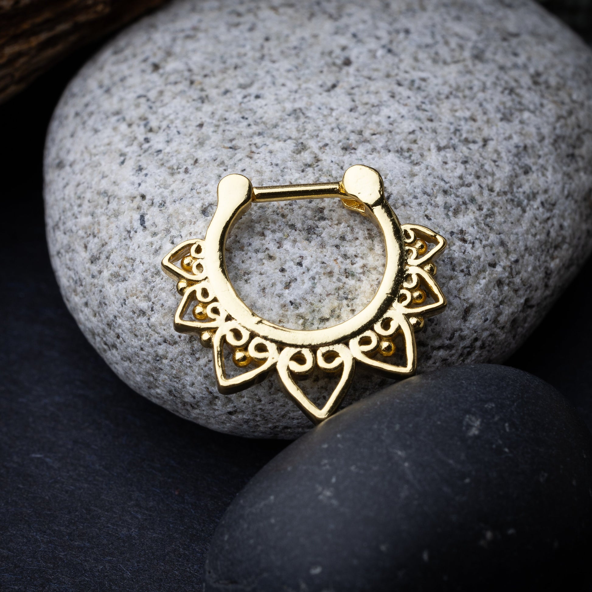 Gold septum clickers with intricate geometric and swirl detailing.