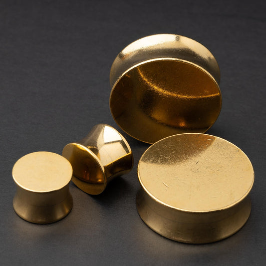 Polished gold plugs in varying sizes, displayed on a dark background.