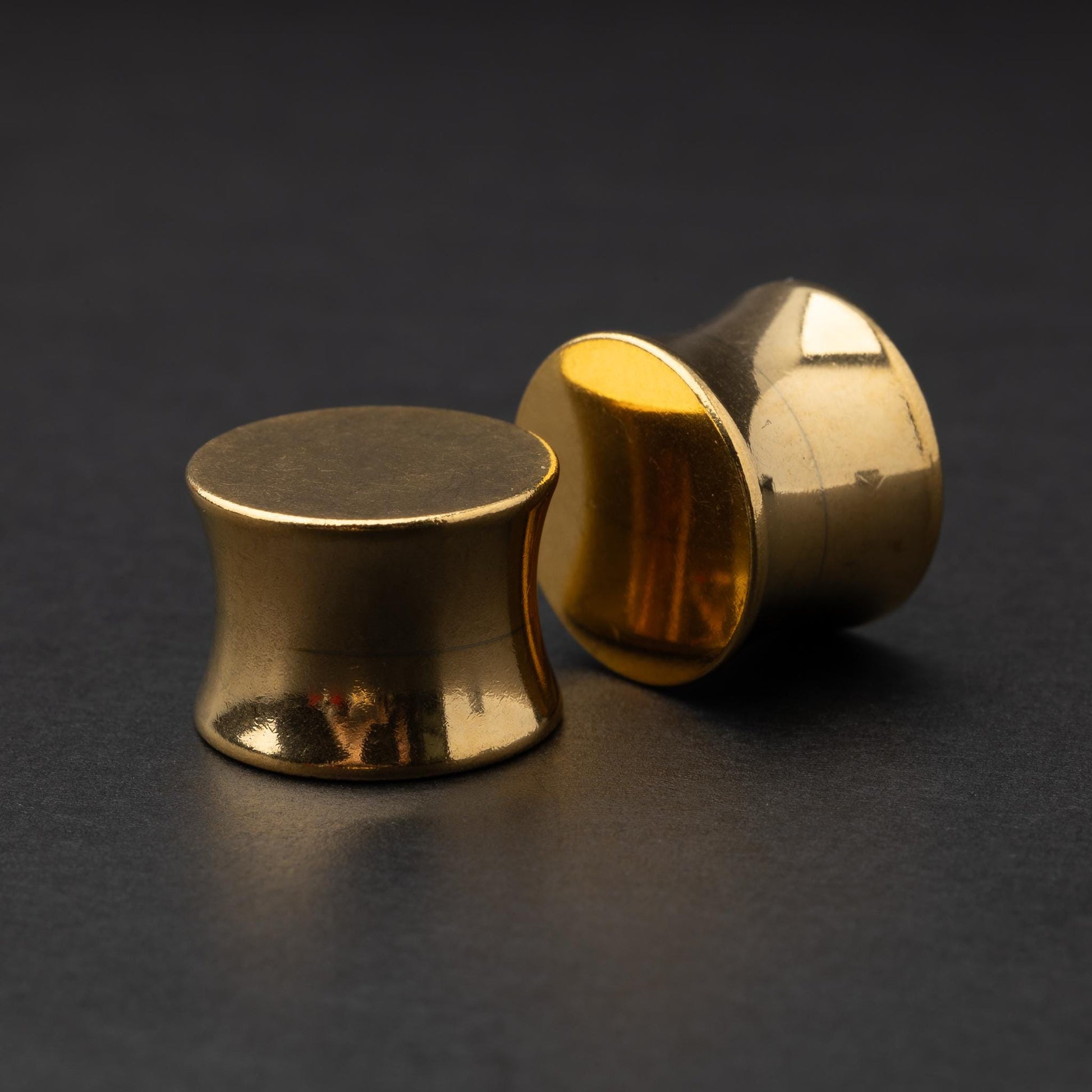 Polished gold plugs displayed on a dark background.