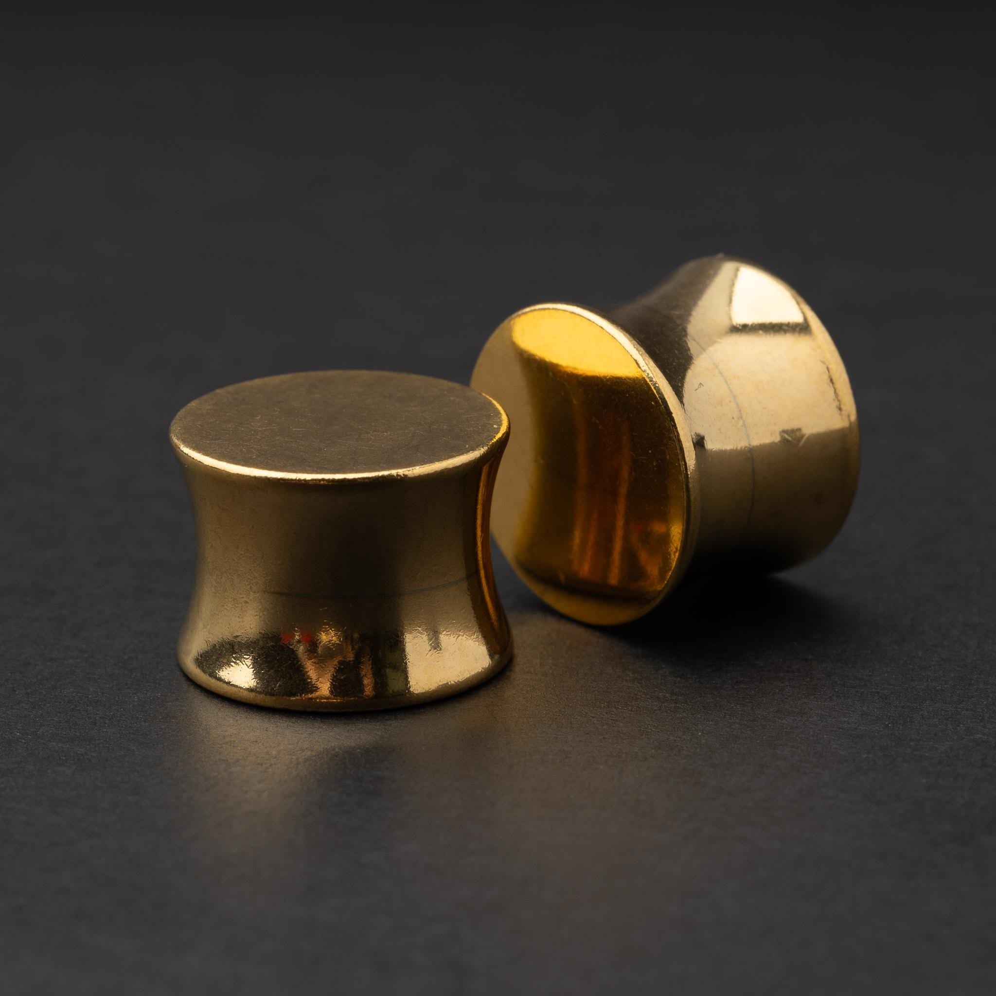 Polished gold plugs displayed on a dark background.
