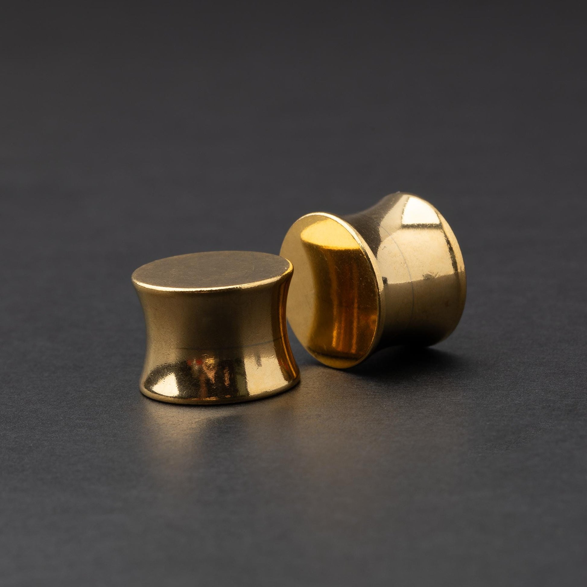 Polished gold plugs displayed on a dark background.