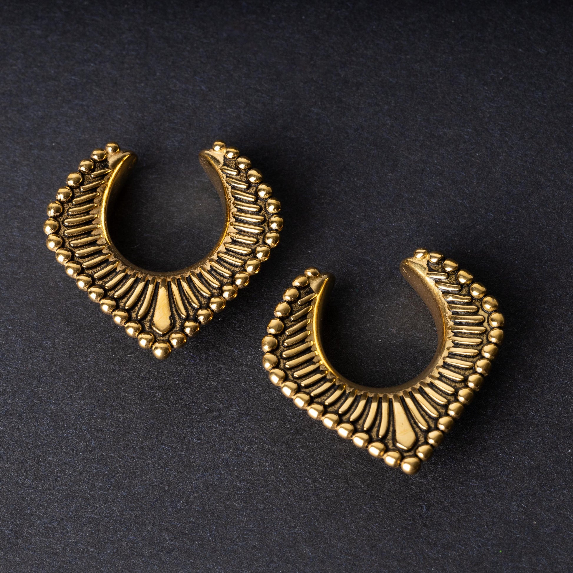 Gold saddle hangers on a dark textured background.