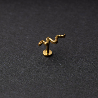 Gold snake motif labret made of stainless steel displayed on a dark background.