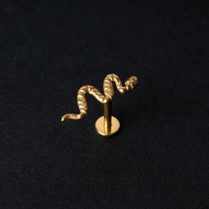 Gold-tone snake labret bar with intricate coiled snake designs displayed on a dark background.

