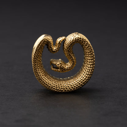 Gold Snake-shaped saddle plugs, displayed on a dark background.