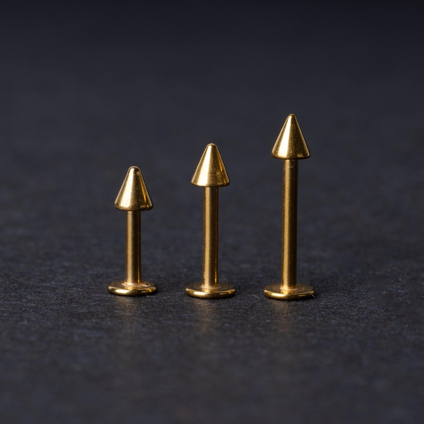 Three sizes of spiked bar back displayed on a dark background.