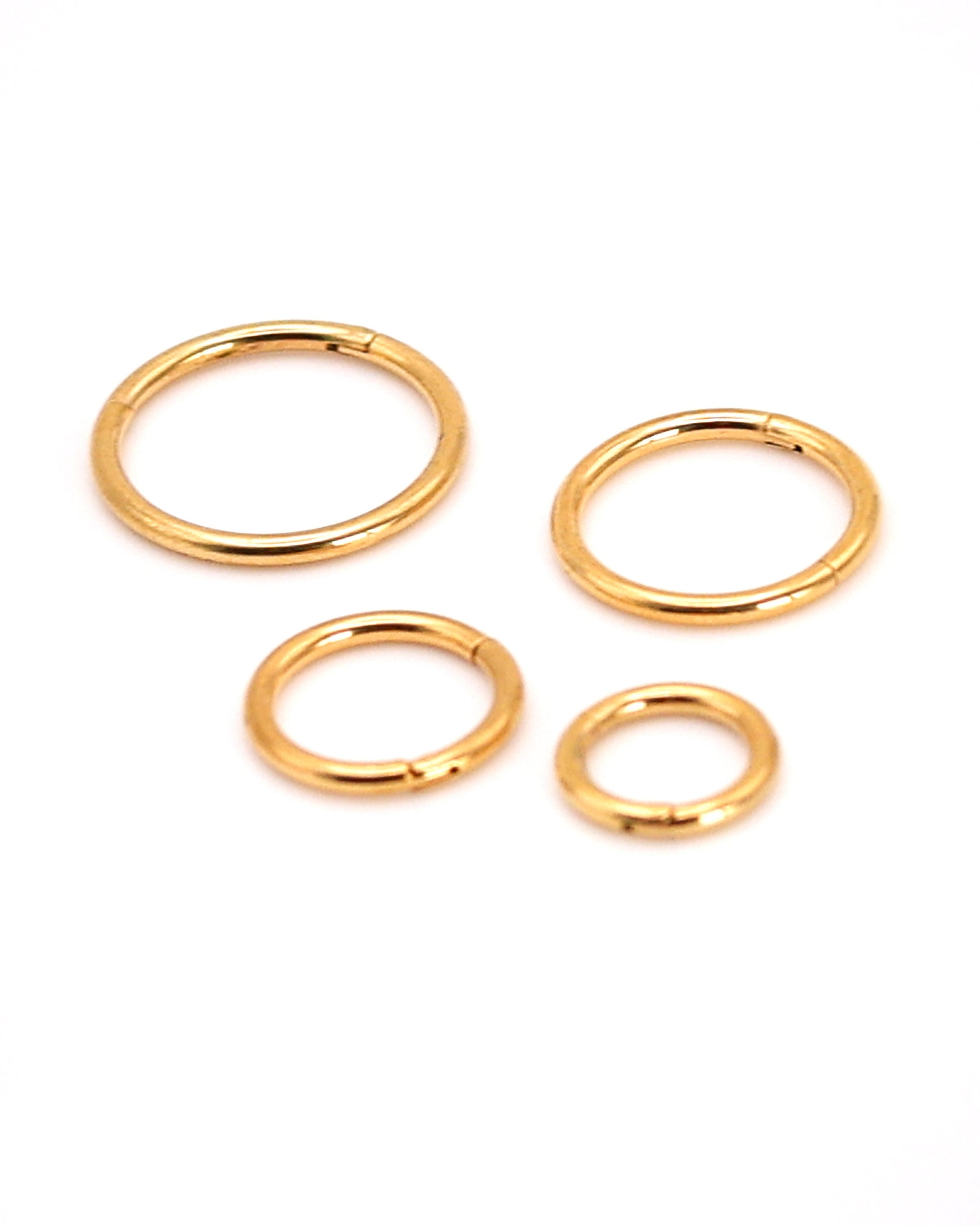 A selection of gold coloured titanium clicker hoops on a white background. 
