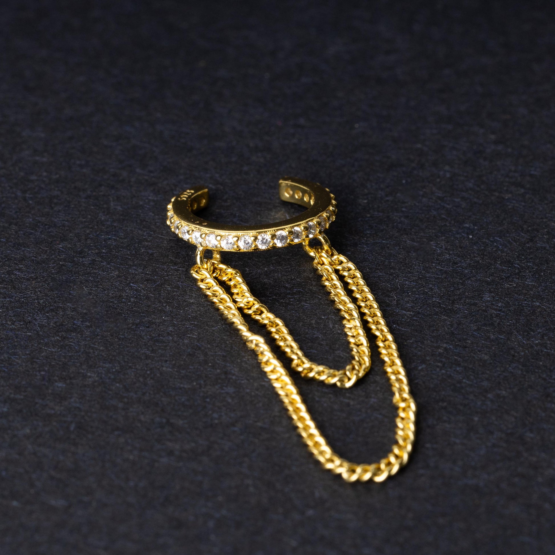 Septum clicker with double chains and gem-encrusted arc, in gold shown on a dark background