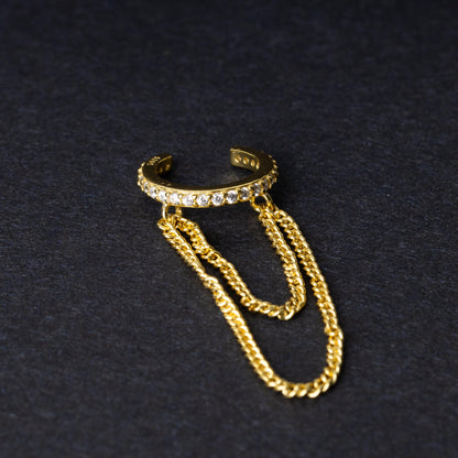 Septum clicker with double chains and gem-encrusted arc, in gold shown on a dark background