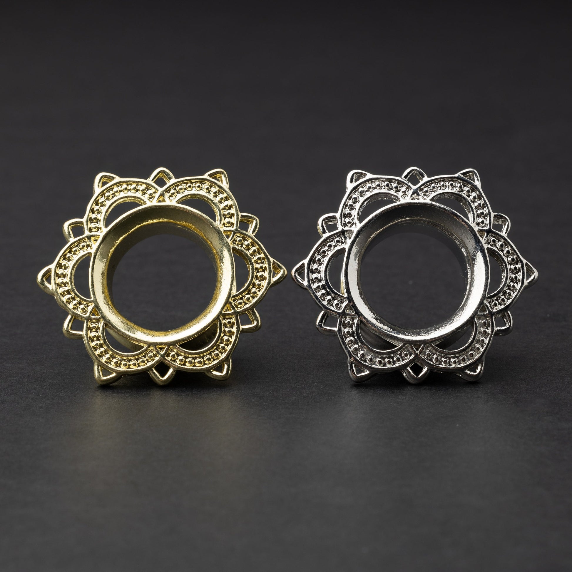 Gold and silver flower-shaped tunnels with intricate detailing, displayed on a dark background.