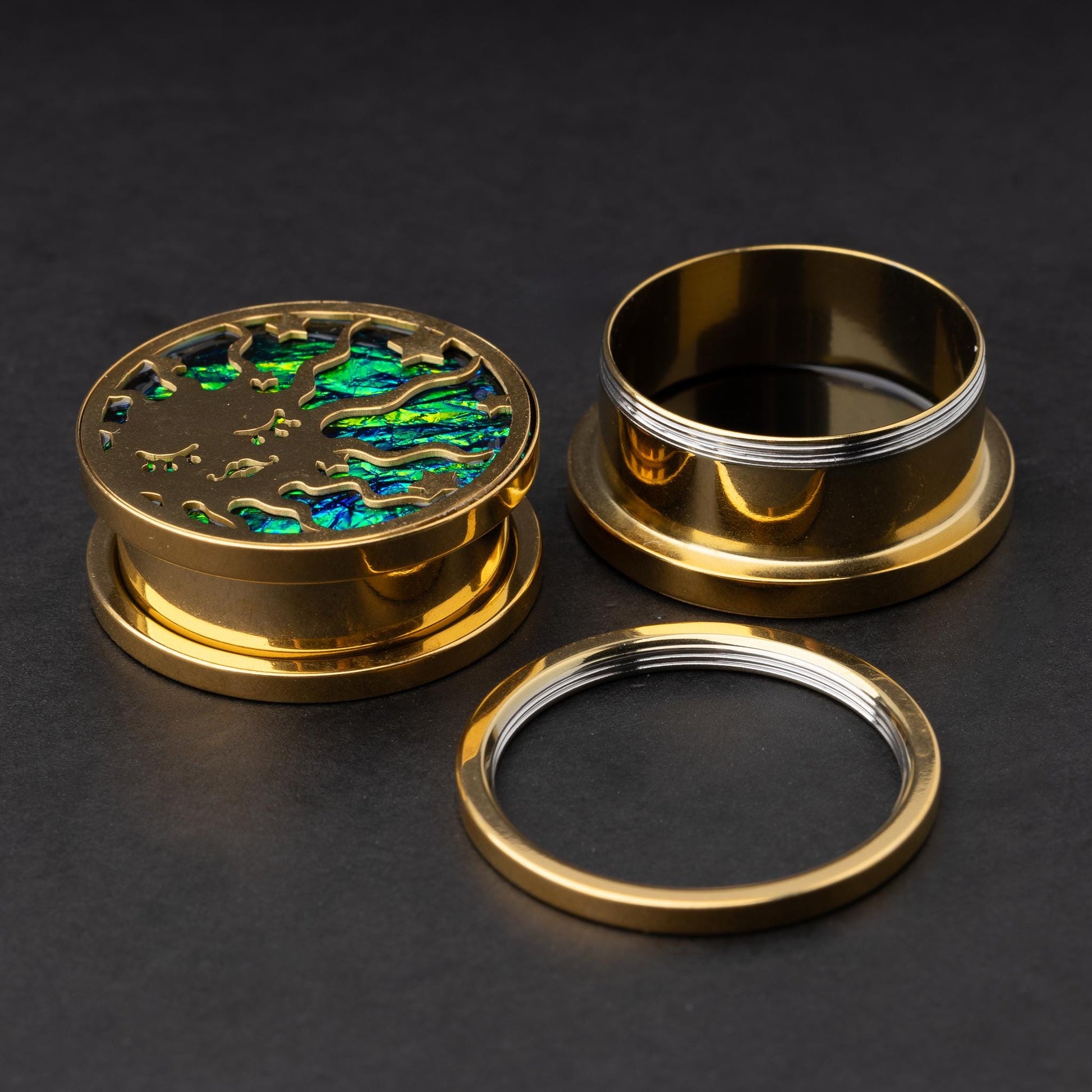 A single sun design gold plug deconstructed, displayed on a dark background