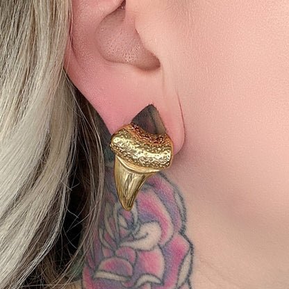 Close-up of gold tooth ear weights on a female with a neck tattoo.

