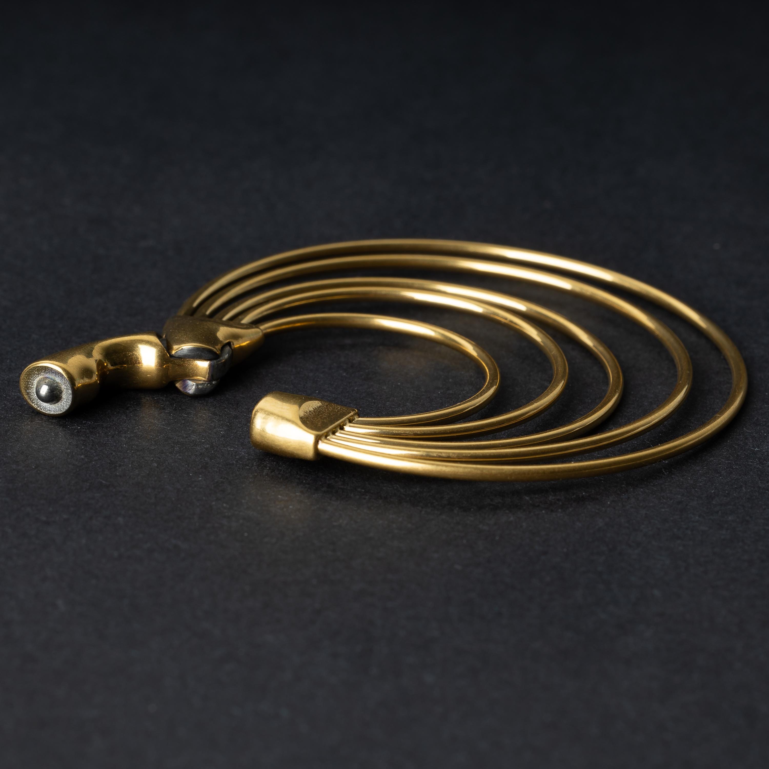 An open multi-hoop ear weight in polished gold, featuring five cascading hoops and a seamless hinge closure, displayed on a dark background.

