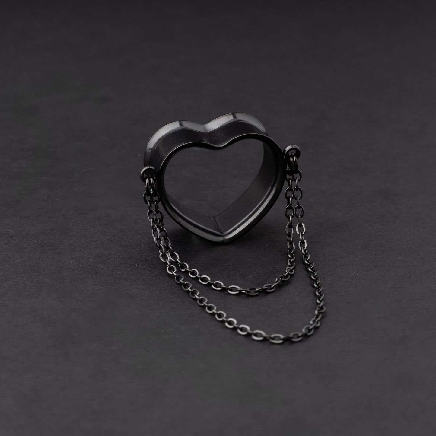 Heart-shaped tunnel with draped chains in black, displayed on a dark background.