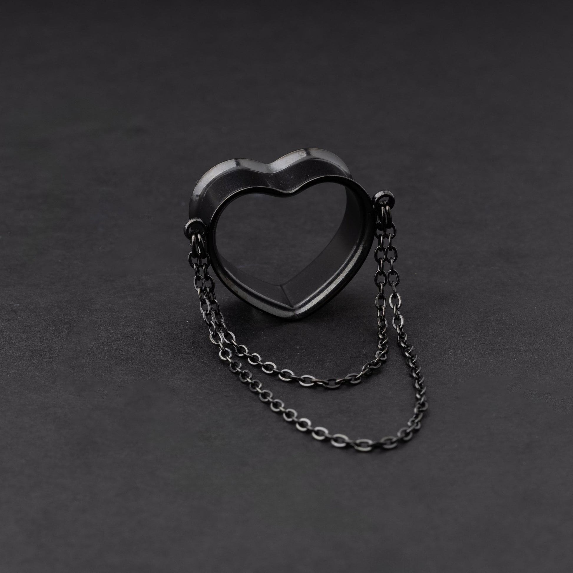 Heart-shaped tunnel with draped chains in black, displayed on a dark background.
