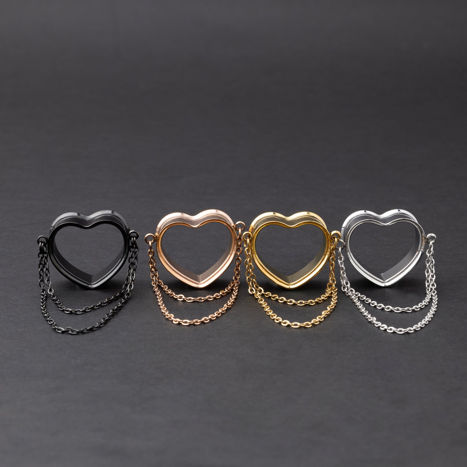 Heart-shaped tunnels with draped chains in black, rose gold, gold, and silver finishes, displayed on a dark background.