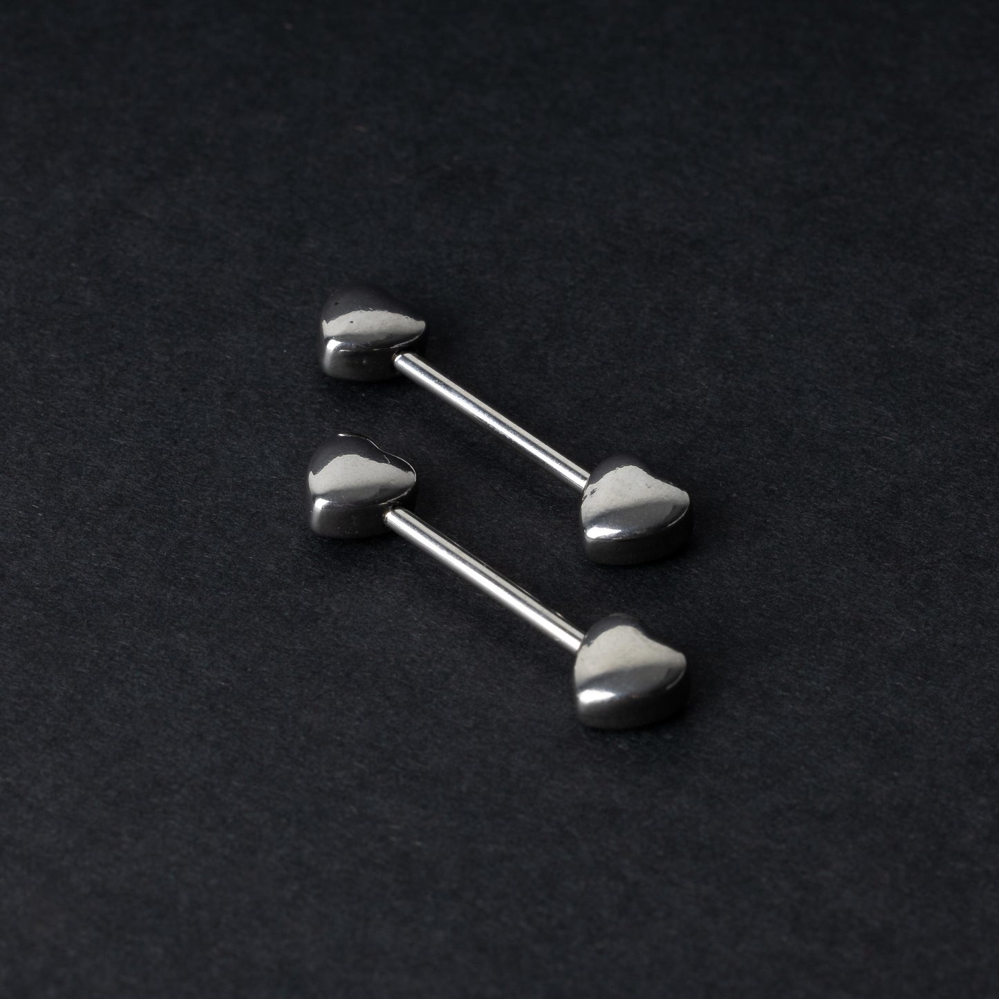 Heart-shaped silver barbells on a dark background.
