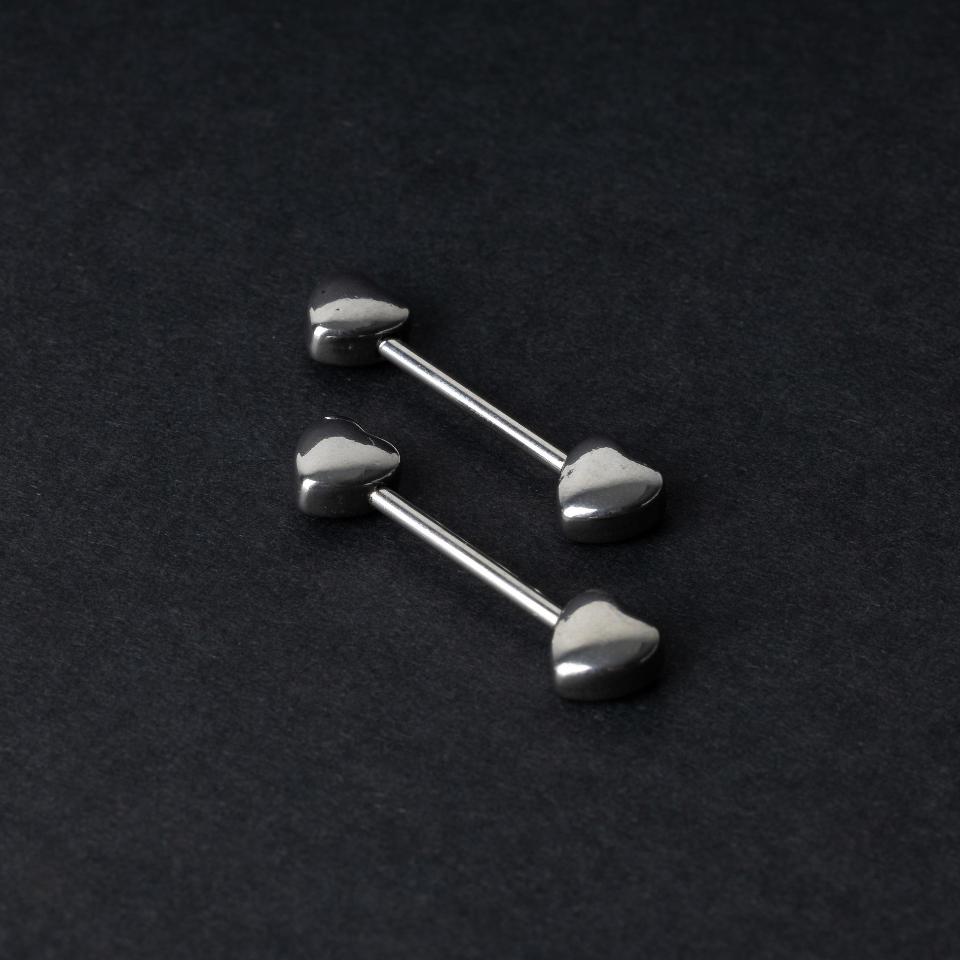 Heart-shaped silver barbells on a dark background.