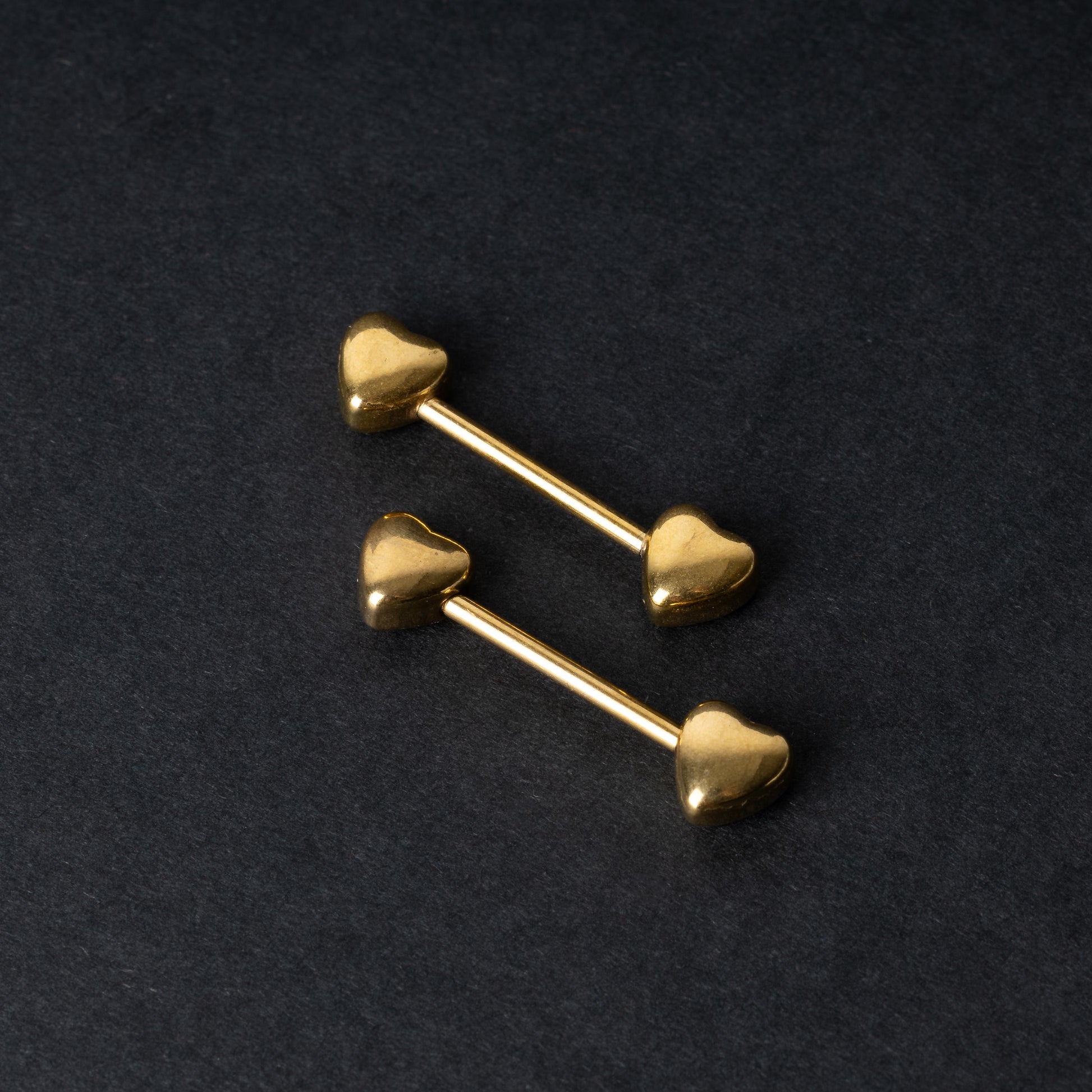Heart-shaped gold barbells on a dark background.