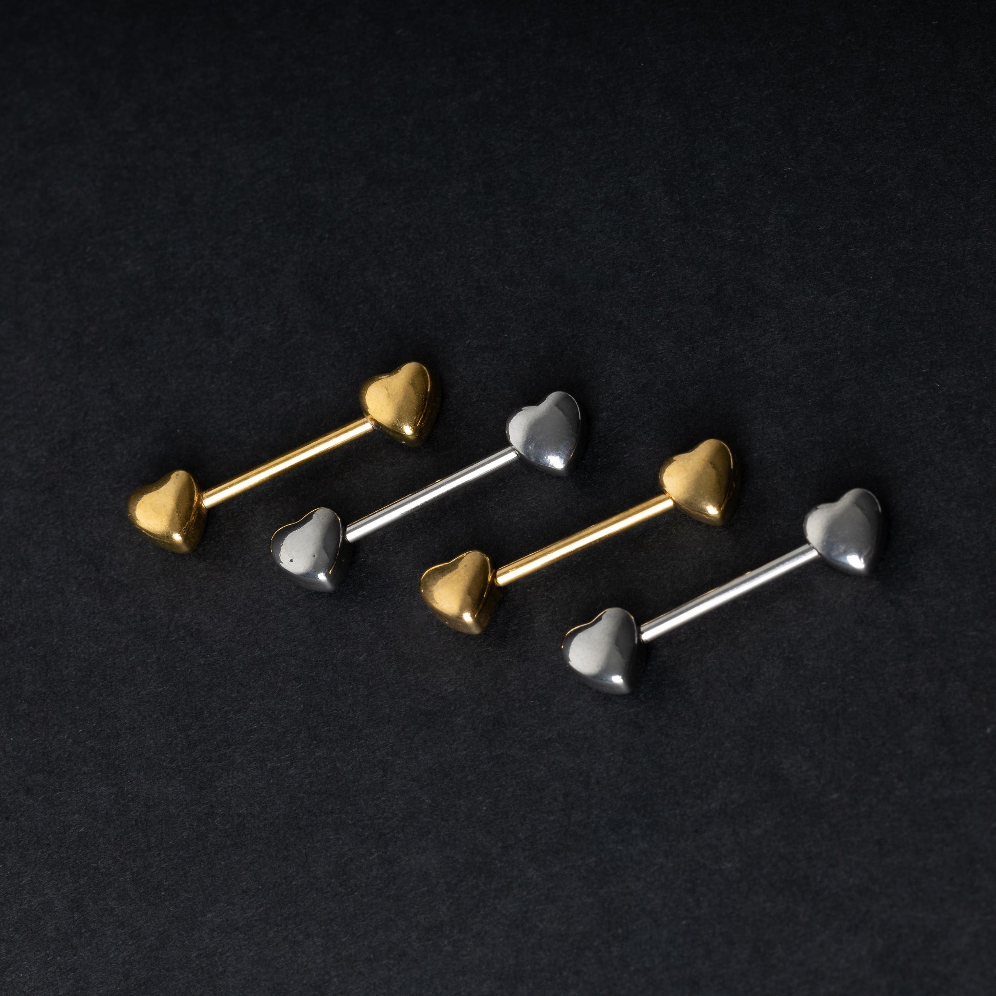 Heart-shaped silver and gold barbells on a dark background.