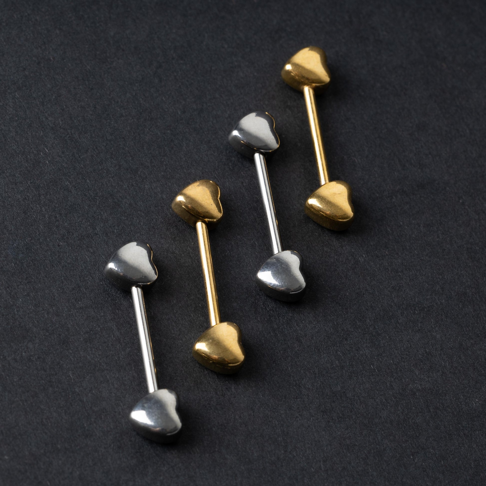Heart-shaped silver and gold barbells on a dark background.