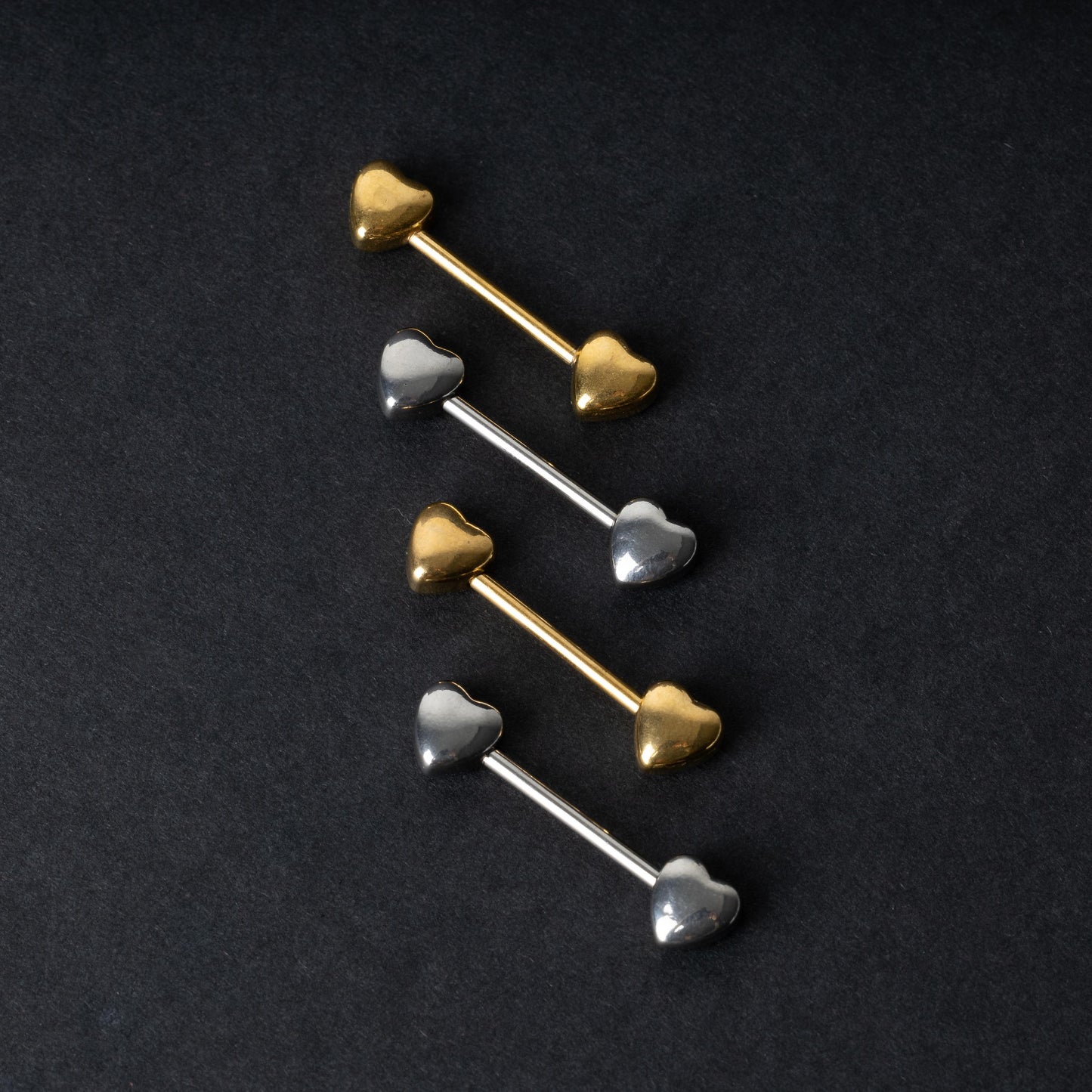 Heart-shaped silver and gold barbells on a dark background.