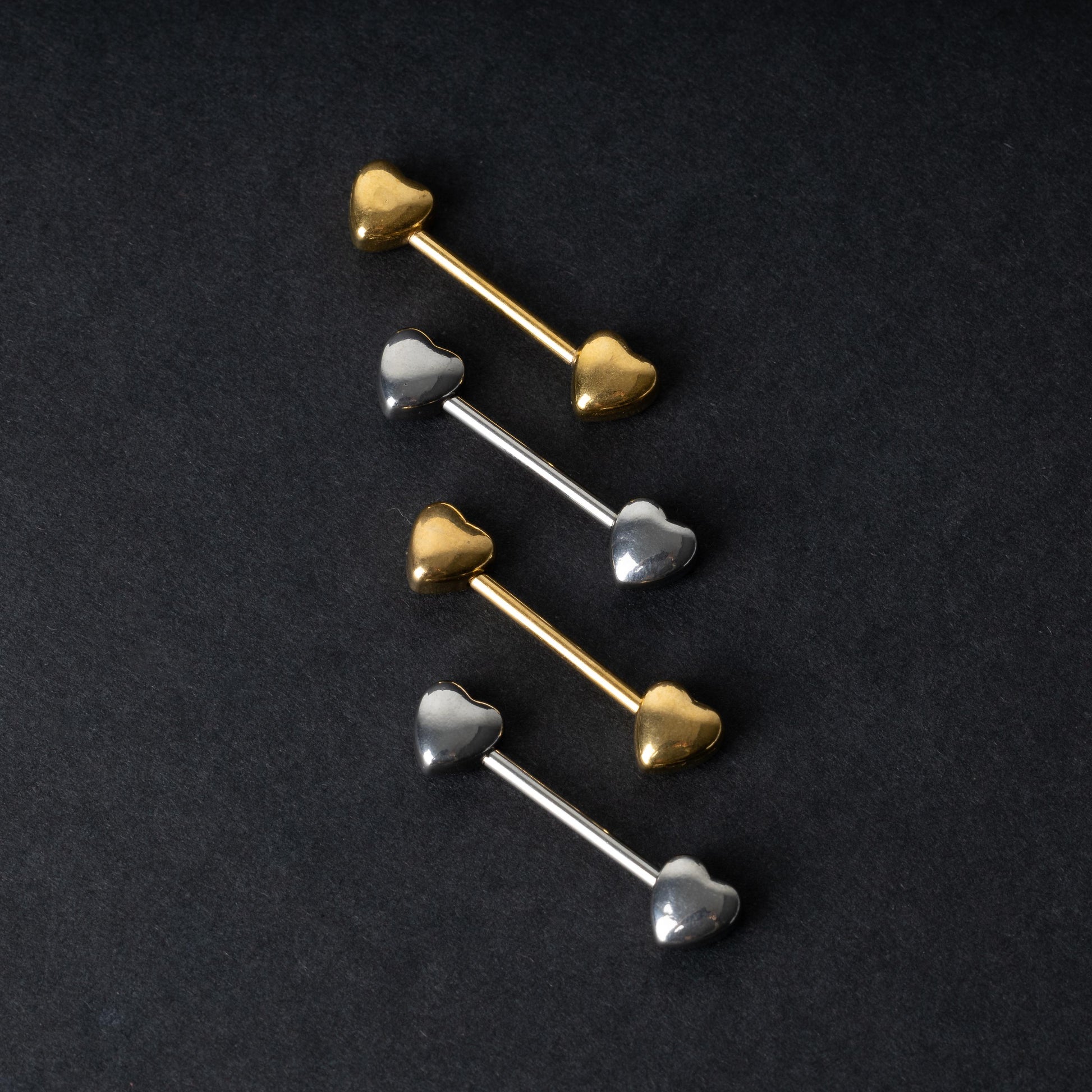 Heart-shaped silver and gold barbells on a dark background.
