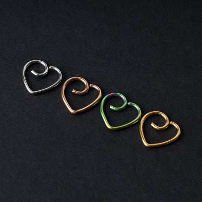 Four heart-shaped nose rings in silver, rose gold, rainbow, and gold finishes, displayed on a dark background.