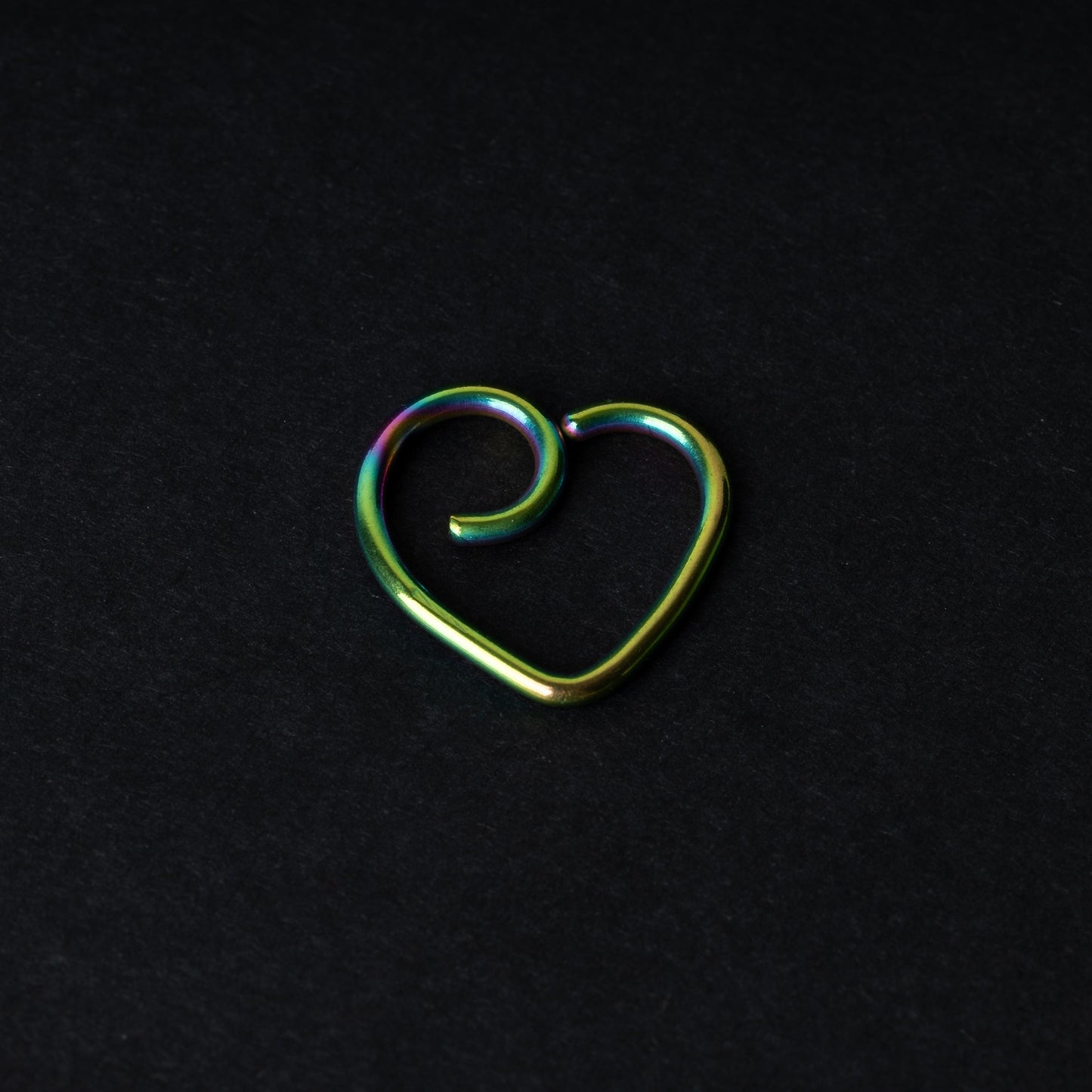 Rainbow heart shaped daith on a dark background
