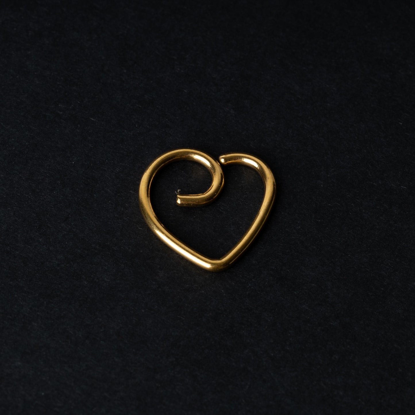 Gold heart shaped daith on a dark background