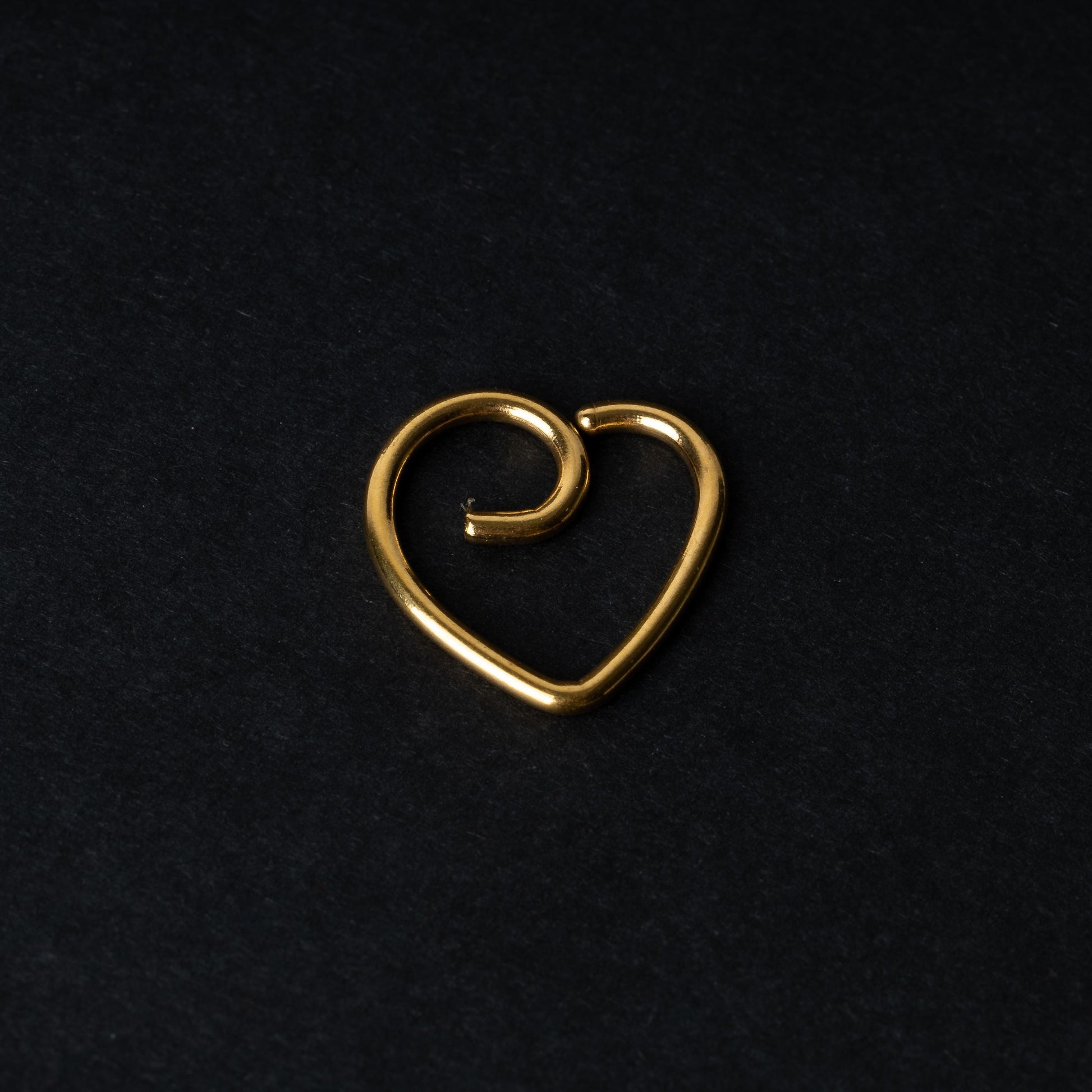 Gold heart shaped daith on a dark background