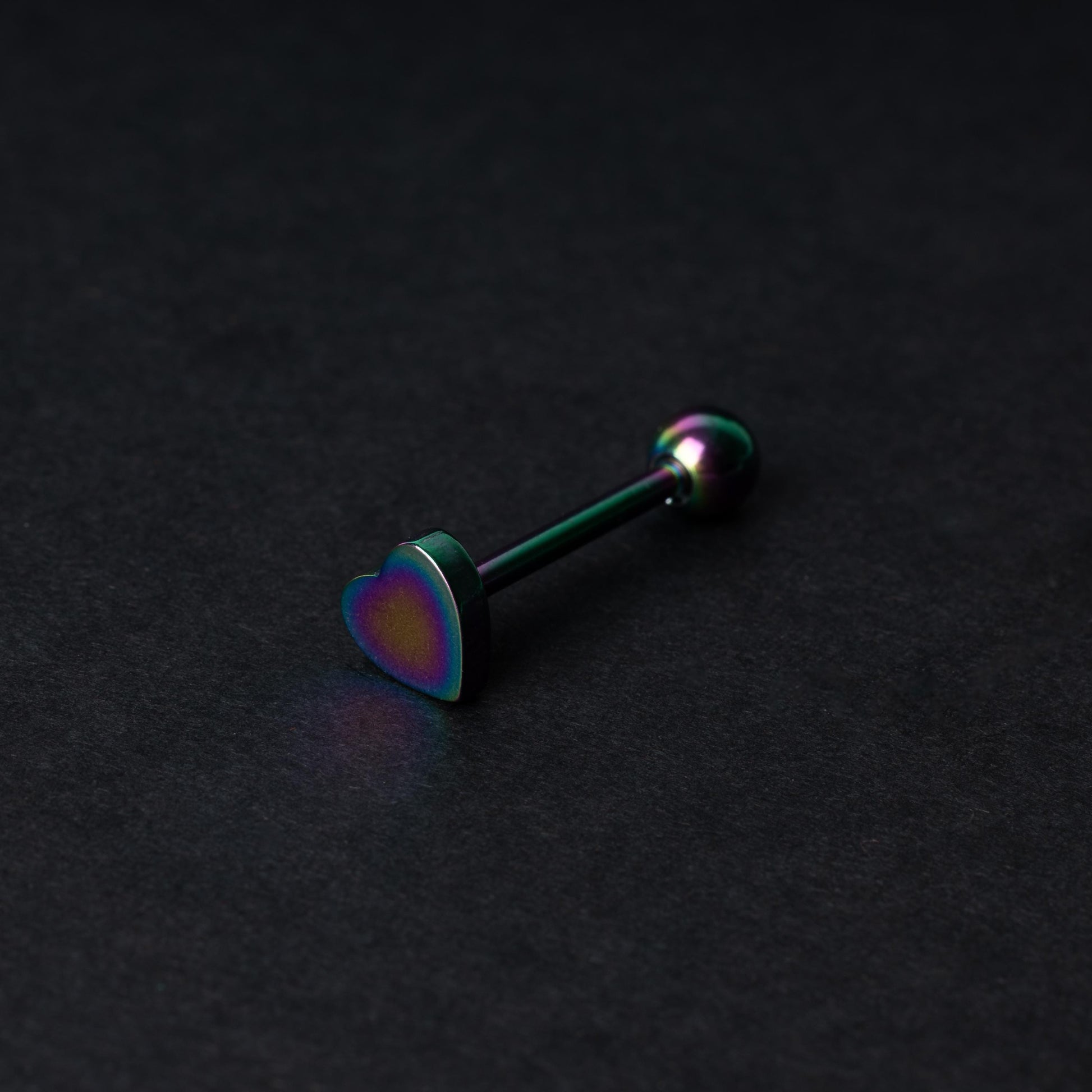 Heart shaped tongue bar in rainbow, displayed on a dark background.