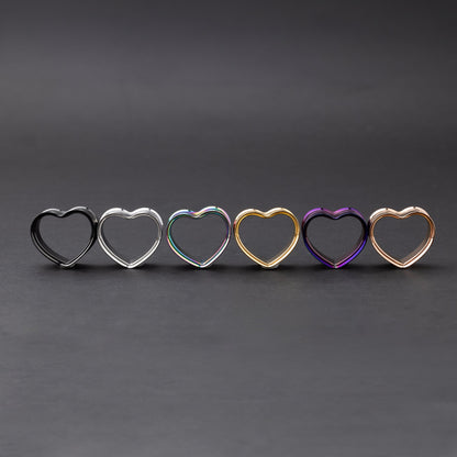 Heart-shaped tunnels in black, silver, rainbow, gold, purple, and rose gold finishes, displayed on a dark background.