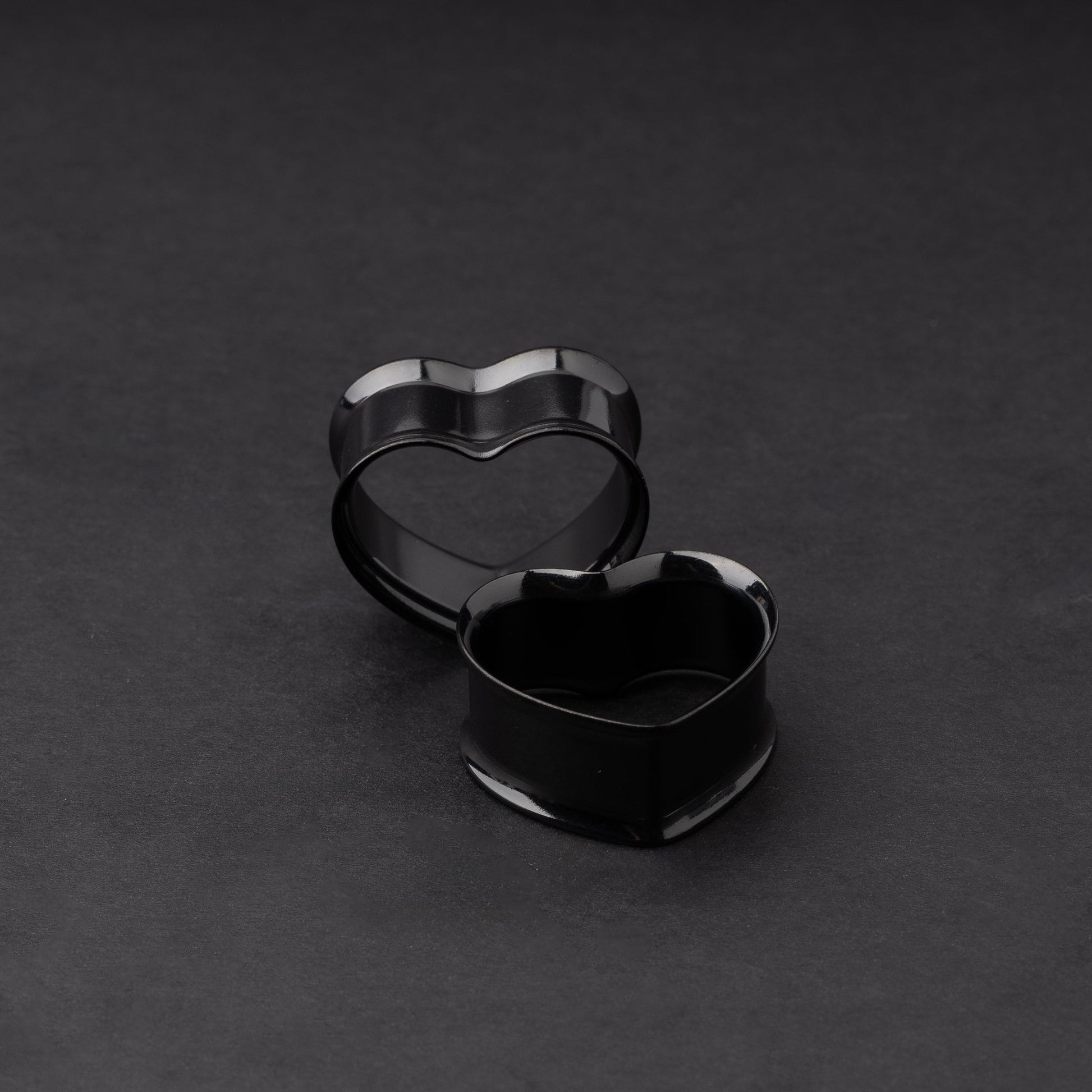 Heart-shaped tunnels in black, displayed on a dark background.