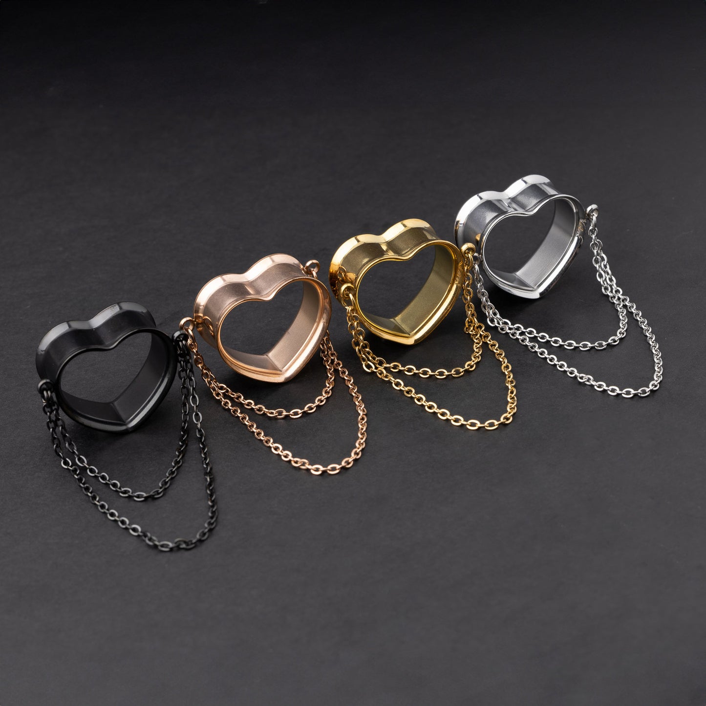 Heart-shaped tunnels with draped chains in black, rose gold, gold, and silver finishes, displayed on a dark background.
