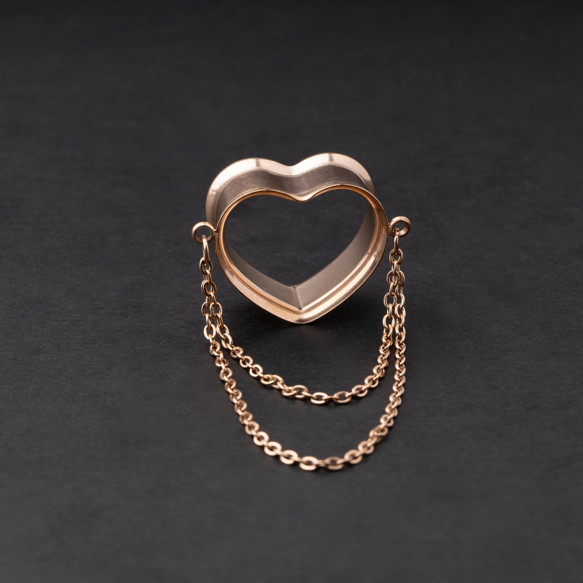 Heart-shaped tunnel with draped chains in rose gold, displayed on a dark background.