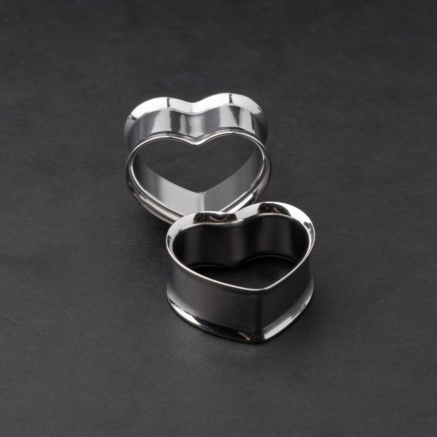Heart-shaped tunnels in silver, displayed on a dark background.